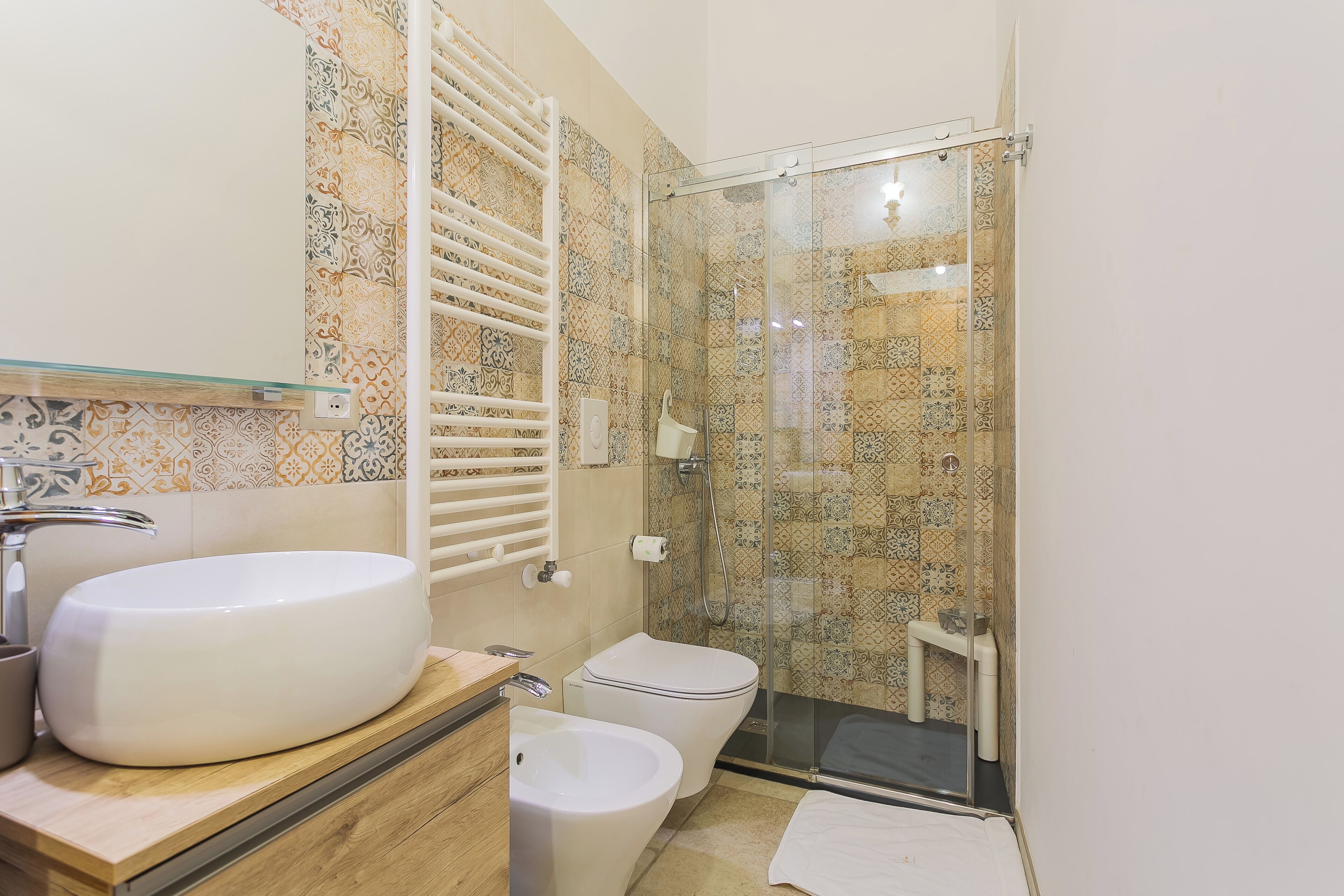 A bathroom with a large sink, toilet, and glass shower enclosure.