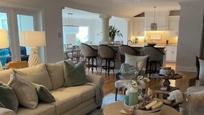 Un salon spacieux avec un canapé beige, une table basse ronde et un ventilateur de plafond.