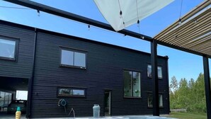 A modern building with a large outdoor hot tub area, a covered patio, and a clear blue sky. - Entire 2Bedroom villa plus jacuzzi 10 min to växjö (Alvesta)
