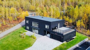 A modern two-story house with a flat roof, large windows, and a covered outdoor area. - Entire 2Bedroom villa plus jacuzzi 10 min to växjö (Alvesta)