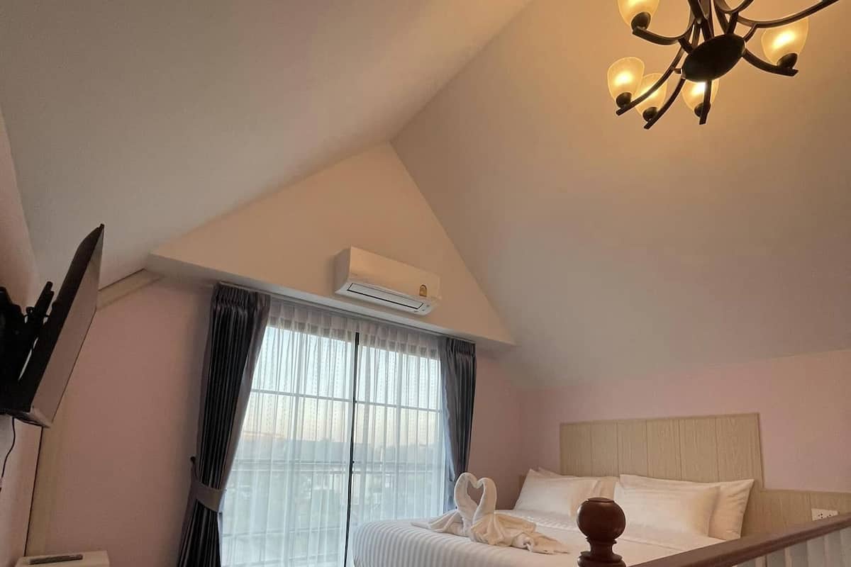 Un dormitorio con cama, candelabro, escalera y unidad de aire acondicionado.