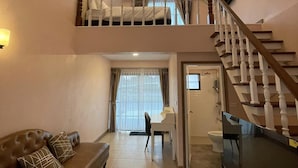A spacious living room with a high ceiling, a staircase leading to an upper level, a large flat-screen TV, and a cozy sofa. - The Autumn Creek ChiangRai (Chiang Rai)
