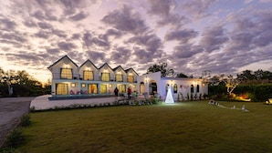 A large, multi-story building with a symmetrical facade, multiple balconies, and a well-maintained lawn. - The Autumn Creek ChiangRai (Chiang Rai)
