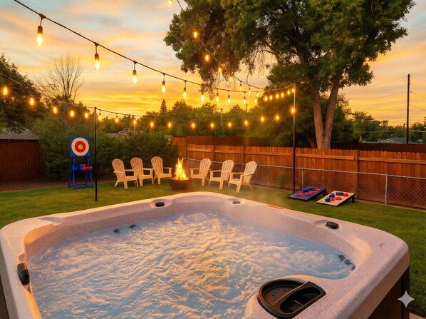 Ein Whirlpool mit Feuerstelle, umgeben von Sitzgelegenheiten und Lichterketten.