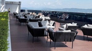 An outdoor seating area with modern furniture and a view of the mountains. - Eaton Residence KLCC By Flixses (Kuala Lumpur)