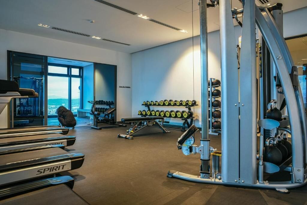 A gym with treadmills, weight machines, and a wall of dumbbells.