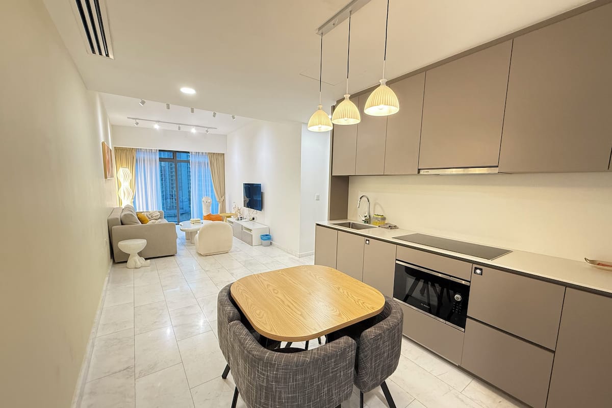 A modern kitchen with a dining area, built-in appliances, and a large window with curtains.