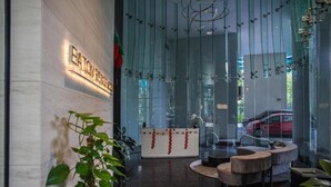 A modern reception area with a glass wall, a reception desk, and a seating area. - Eaton Residence KLCC By Flixses (Kuala Lumpur)