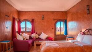 A cozy room with a bed, a sofa, and two windows with curtains. - Sud-Est Palace guest House Kalaa m'gouna (Ait Sedrate Sahl El Gharbia)