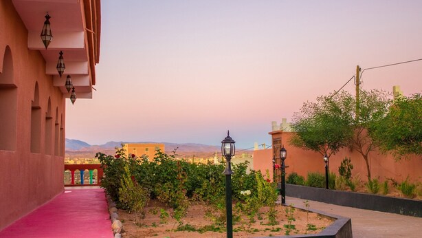 A corridor with a pink carpet, a garden with roses, and a view of distant mountains. - Sud-Est Palace guest House Kalaa m'gouna (Ait Sedrate Sahl El Gharbia)