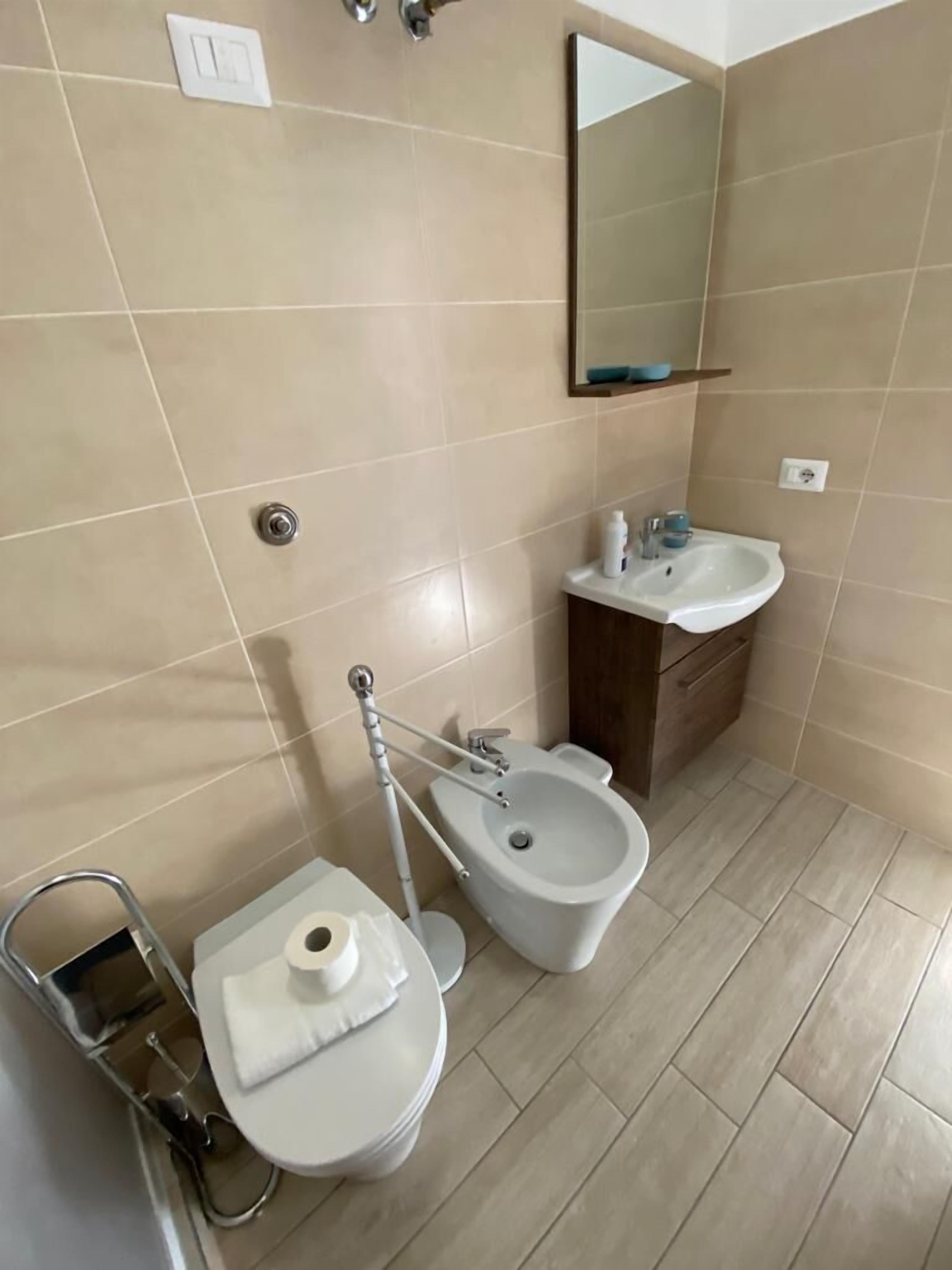 A bathroom with a toilet, bidet, sink, and mirror.
