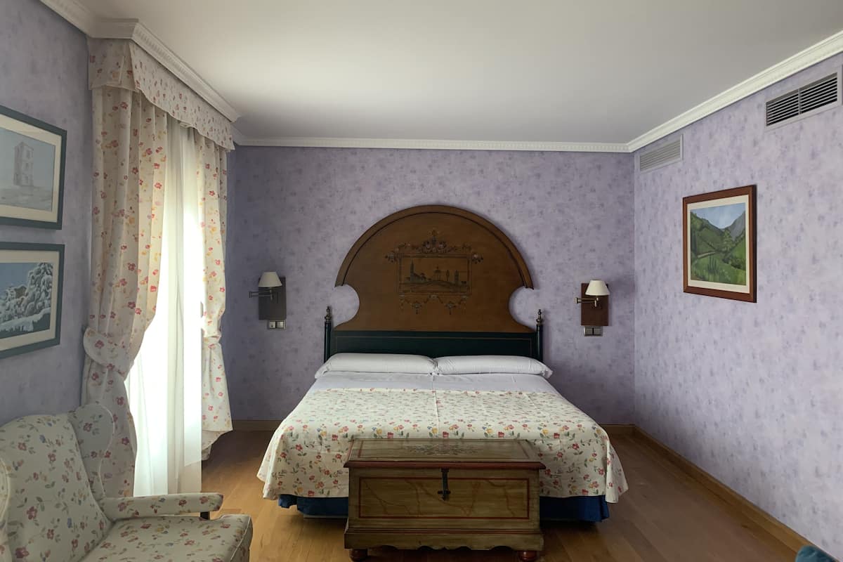 Une chambre à coucher comprenant un lit, une table de chevet, une chaise et deux lampes fixées au mur.
