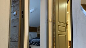 A hallway leading to a bedroom with a bed and a wooden floor. - Superbe Duplex aux Pieds des Pistes (Vars)