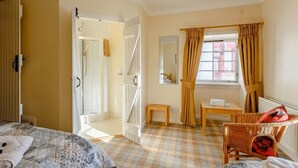 A hotel room with a checkered floor, a bed, a chair, a small table, and a window with curtains. - Gorgeous NC500 getaway in the Highlands, 30 miles - John O'Groats Sleeps up to 6 (Latheronwheel)