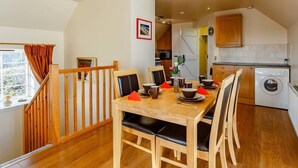 A dining area with a wooden table and chairs, a kitchen with a washing machine, and a staircase. - Gorgeous NC500 getaway in the Highlands, 30 miles - John O'Groats Sleeps up to 6 (Latheronwheel)