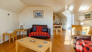 A spacious living area with a sofa, coffee table, and a dining area in the background. - Gorgeous NC500 getaway in the Highlands, 30 miles - John O'Groats Sleeps up to 6 (Latheronwheel)