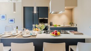 A modern kitchen with a central island, white chairs, and a dining table set for four. - Casa Pino in Lucca With 2 Bedrooms and 2 Bathrooms (Lucca)