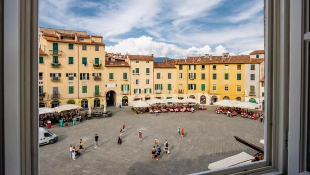 A courtyard with buildings, outdoor seating, and a clear sky. - Casa Pino in Lucca With 2 Bedrooms and 2 Bathrooms (Lucca)