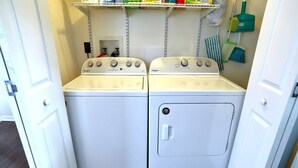 A laundry room with two Whirlpool washers and dryers, a shelf with cleaning supplies, and a broom. - 2BR/1BA Cozy Retreat near Timberline slopes (Davis)