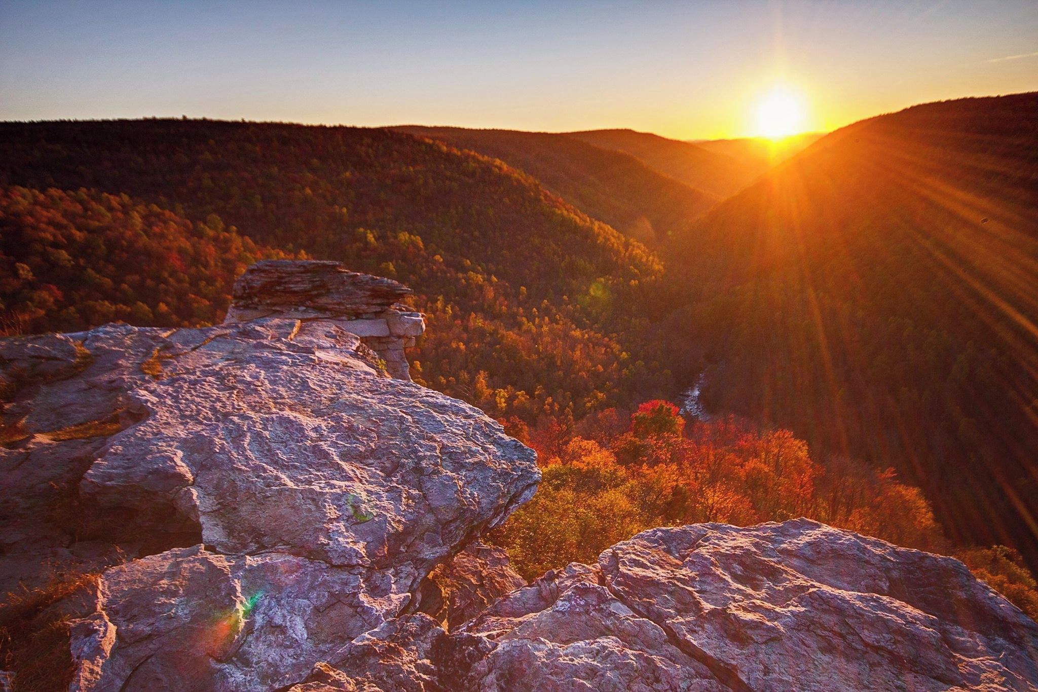 Un paysage montagneux avec une formation rocheuse imposante au premier plan et un coucher de soleil en arrière-plan.