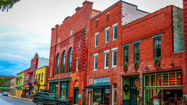 A row of colorful brick buildings with various storefronts, including a shop named 'Riverfront Antiques'. - 2BR/1BA Cozy Retreat near Timberline slopes (Davis)