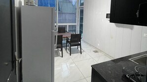 Une cuisine moderne avec un plan de travail noir, un réfrigérateur blanc et un coin repas comprenant une table et des chaises.