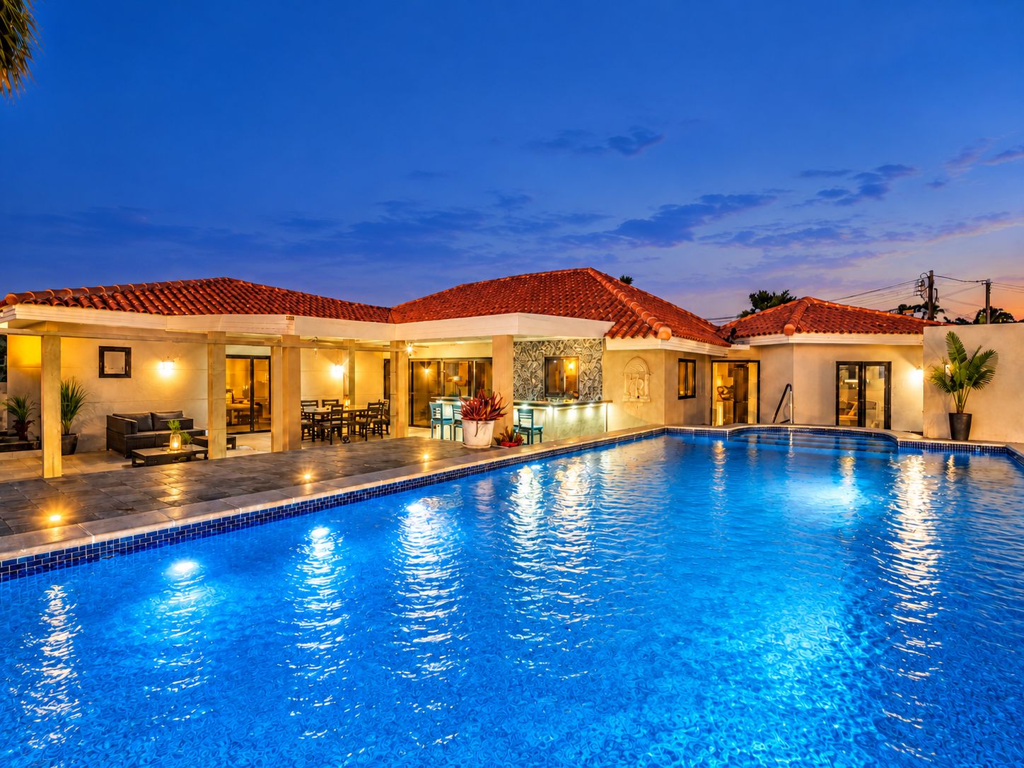 A swimming pool with a tiled deck, a bar area, and a covered seating area.