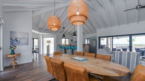 A spacious dining area with a large wooden table, leather chairs, and woven pendant lights. - Ruby On The Salina: Pool, Bar & Stunning View - 4 Minutes to Beaches! (Noord)