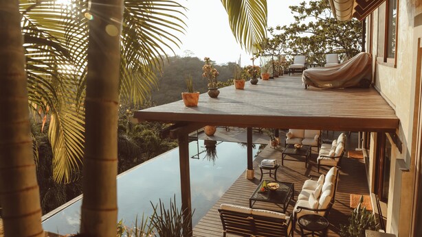 A wooden deck with outdoor seating, a pool, and potted plants.