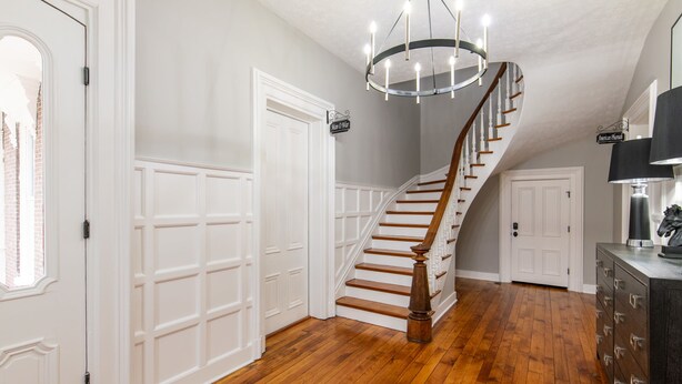 A staircase with wooden steps and a white wall. There is a door with a sign above it.