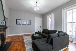 Una sala de estar con un sofá seccional, una chimenea y cuadros en la pared.