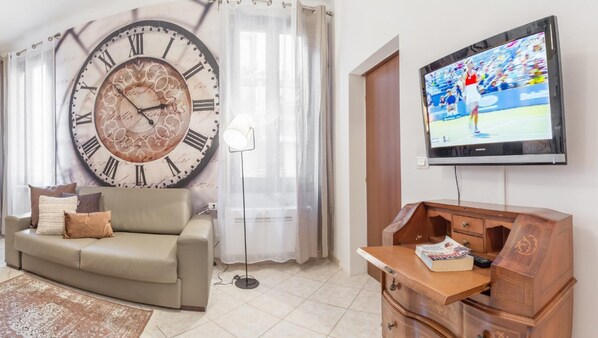 A living room with a large wall clock, a television, a sofa, and a wooden cabinet. - Venice Grand Canal Style Apt 1 by Wonderful Italy (Venice)