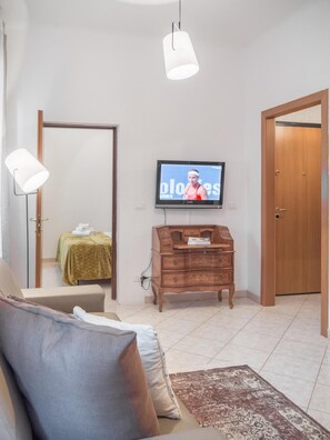 A room with a bed, a wooden dresser, a television on the wall, and a door. - Venice Grand Canal Style Apt 1 by Wonderful Italy (Venice)