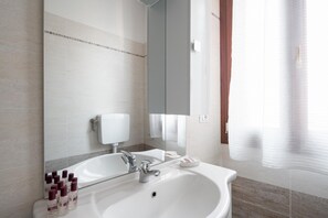Une salle de bain moderne avec un grand lavabo, un miroir et des articles de toilette.