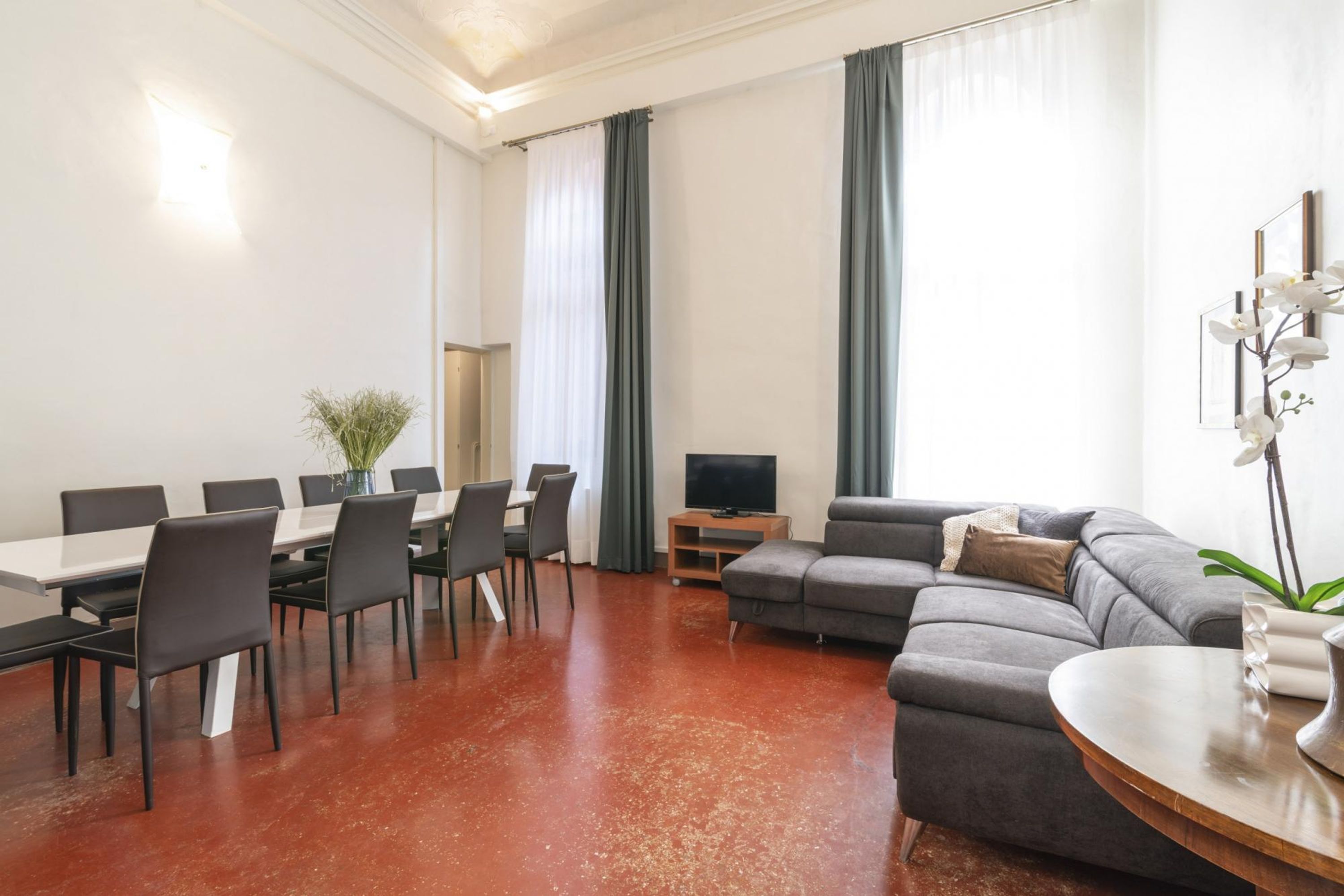 Een moderne woonkamer met een eethoek, een grijze bank en een tv-meubel.