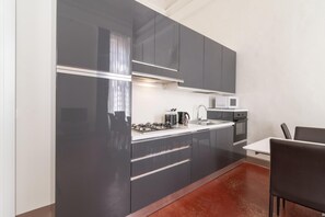 A modern kitchen with dark cabinets, stainless steel appliances, and a white countertop. - Venice Luxury Palace 12 by Wonderful Italy (Venice)