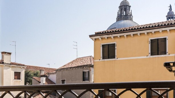 A courtyard with buildings, including a yellow building with a dome and a bell tower. - Accademia Charm 4 by Wonderful Italy (Venice)