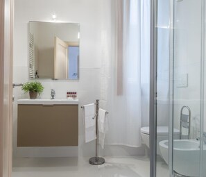 Ein modernes Badezimmer mit einer Duschkabine aus Glas, einem Waschbecken und einem Spiegel über dem Waschtisch.