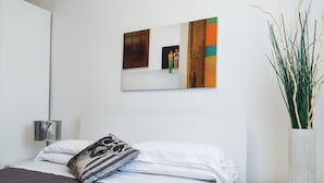 Een hotelkamer met een bed, nachtkastje, lamp, spiegel en een sierplant.