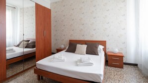 Una camera d'albergo con un letto, un armadio in legno, un comodino e uno specchio.