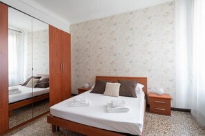 Une chambre d’hôtel avec un lit, une armoire en bois, une table de chevet et un miroir.