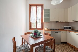 Una cocina compacta con una mesa de comedor, sillas, microondas y lavavajillas.