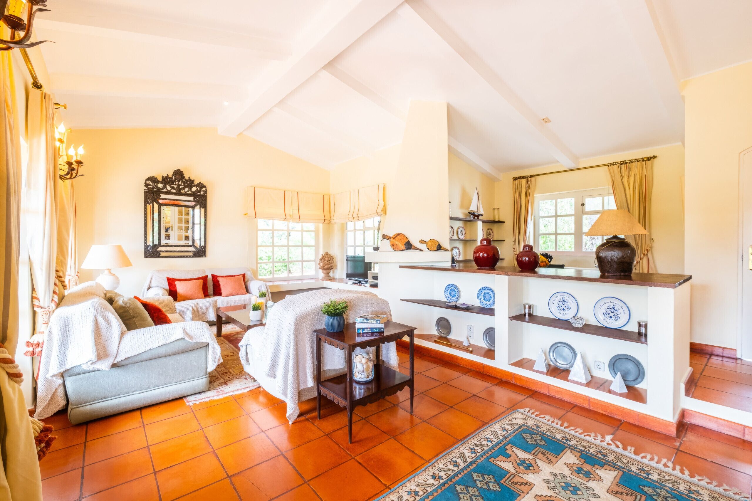 Amplia sala de estar con sofá, mesa de centro y televisor. Hay una zona de cocina con pileta y estufa.