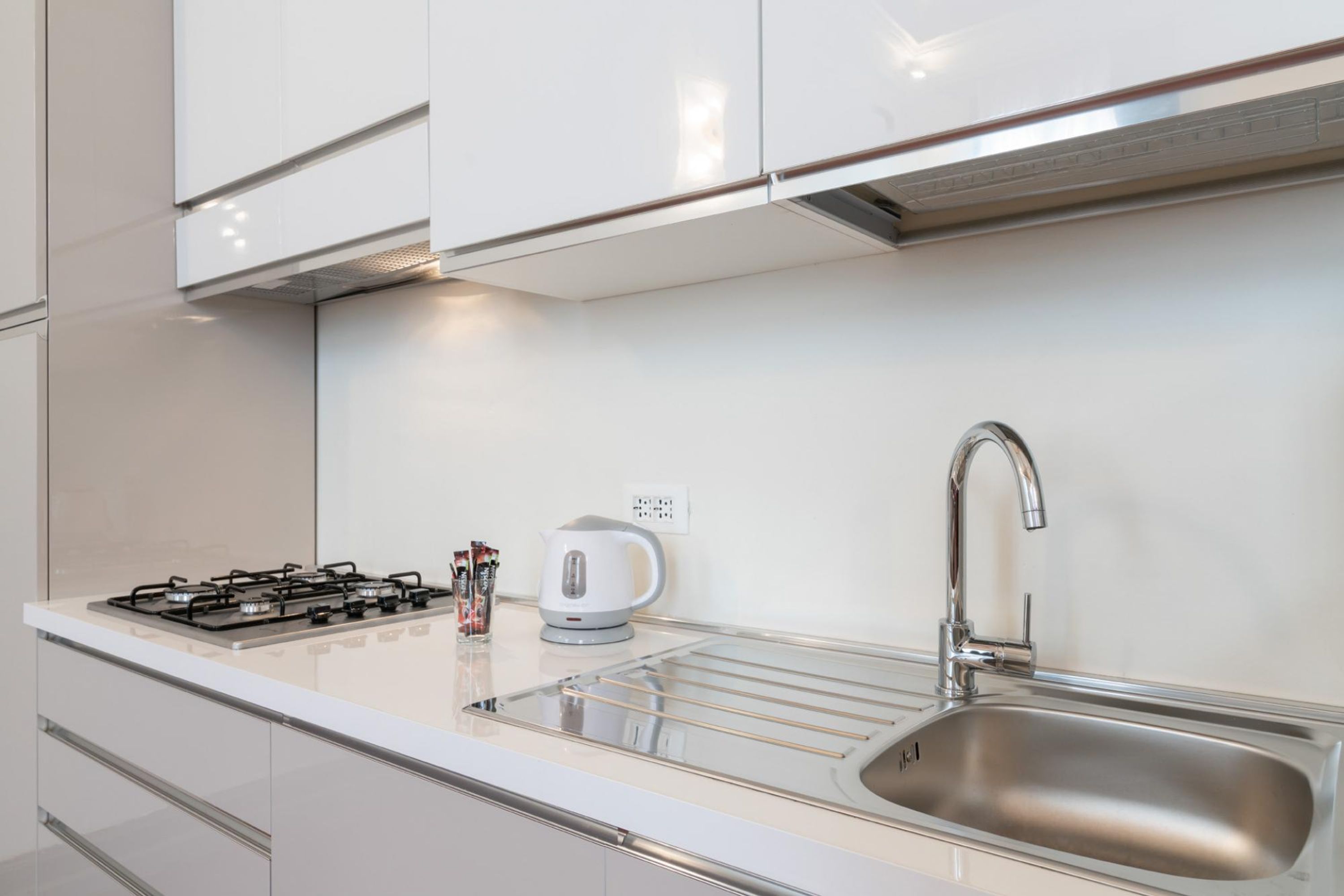 A modern kitchen with a stainless steel sink, a gas stove, and a kettle.