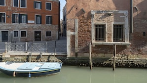 A canal with a boat docked at a wooden pier. - San Marco Style Canal View Apt 1 by Wonderful Italy (Venice)