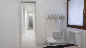 A bedroom with a bed, a radiator, a window with curtains, a hanging clothes rack, and a door leading to another room. - San Marco Style Canal View Apt 1 by Wonderful Italy (Venice)