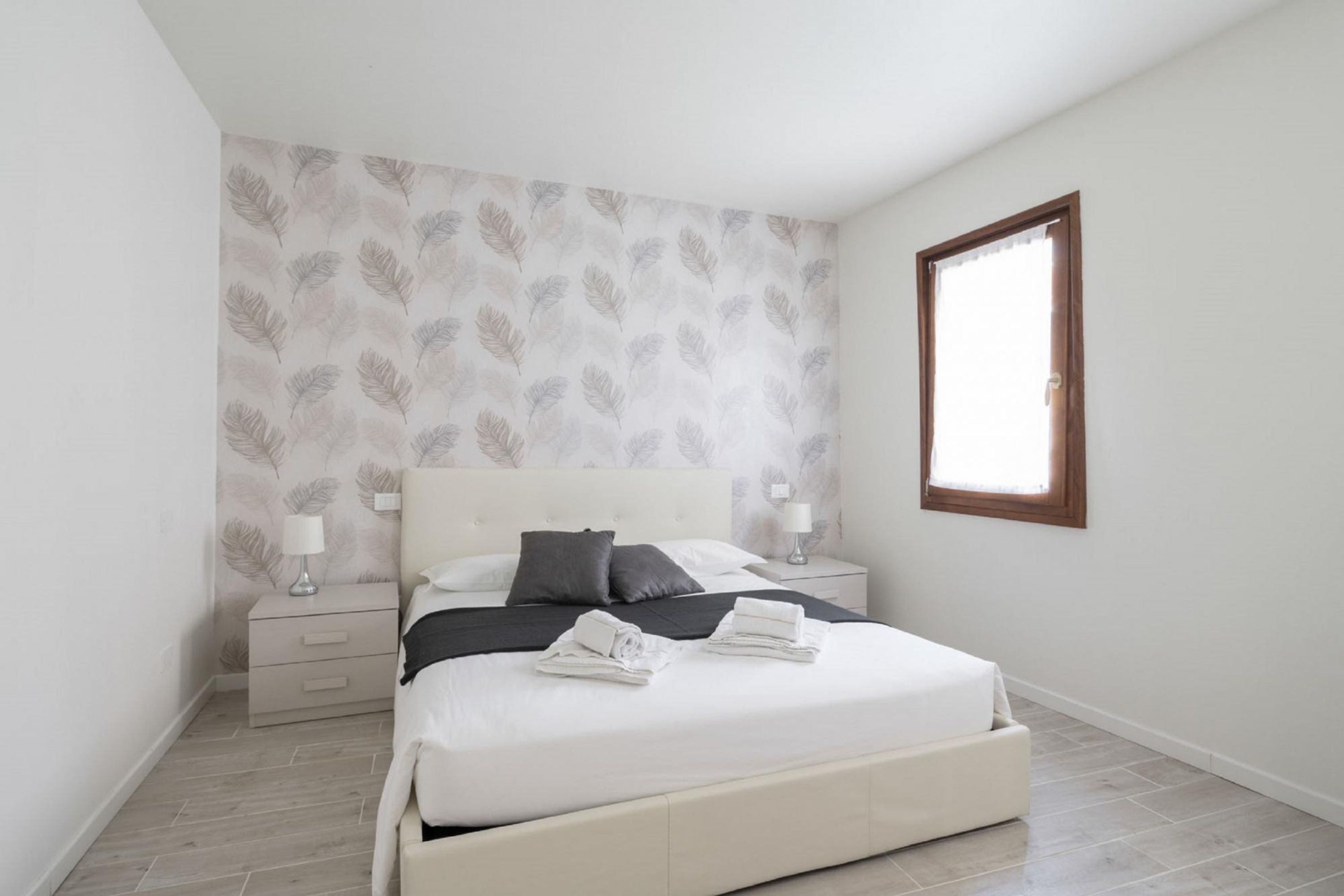 Een slaapkamer met een bed, nachtkastjes en een raam.