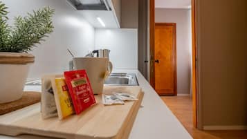Uma cozinha com uma tábua de corte, um vaso de planta, uma chaleira e alguns pacotes de comida.