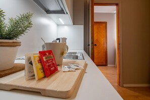Et køkken med skærebræt, en potteplante, en elkedel og madpakker.