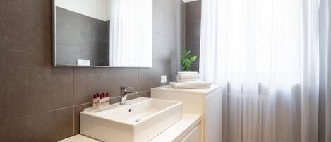 A modern bathroom with a large mirror, a white sink, and a toilet.